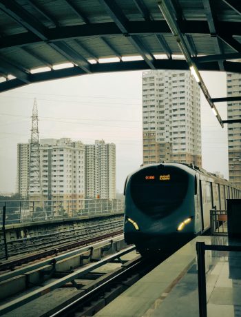 Kochi metro train arriving at a modern urban station with high-rise buildings in the background.