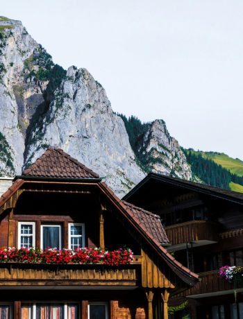 Rustic wooden houses with vibrant flower boxes set against majestic alpine mountains.
